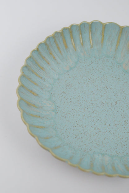 Light blue ceramic pasta bowl with textured surface and decorative edge on a white background