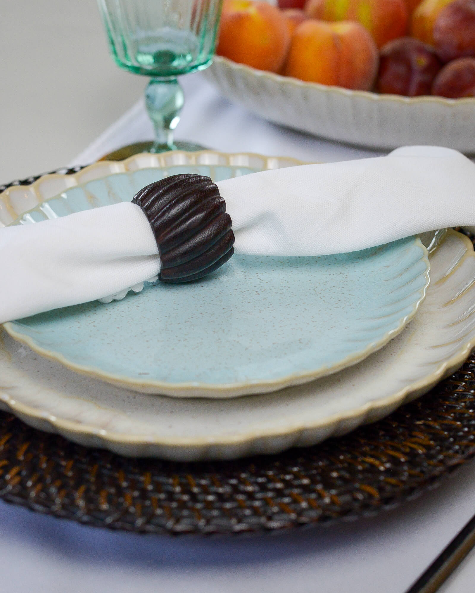 Stacked ceramic stoneware plates in white and light blue with a napkin and decorative item on a table setting.