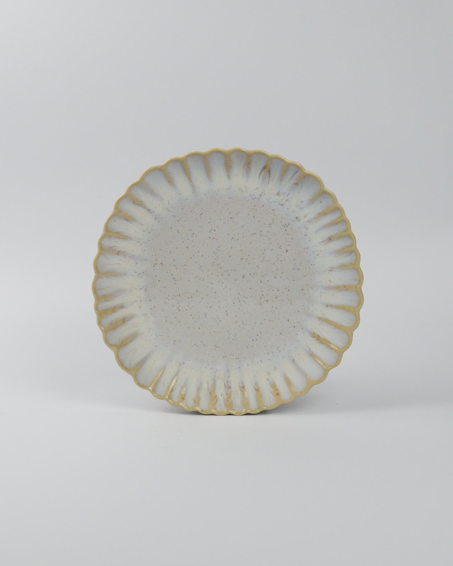 Ceramic salad plate with textured surface and scalloped edge on a white background