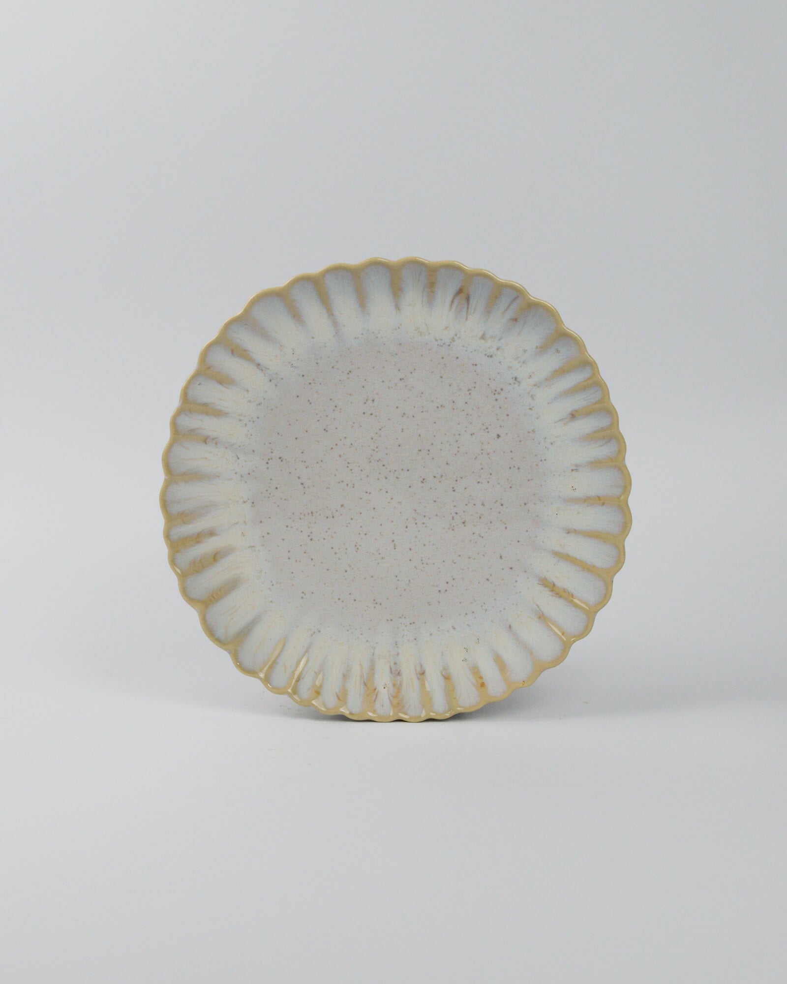 Ceramic salad plate with textured surface and scalloped edge on a white background