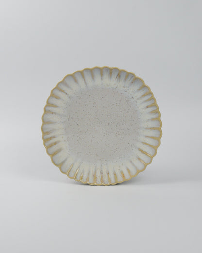Ceramic salad plate with textured surface and scalloped edge on a white background