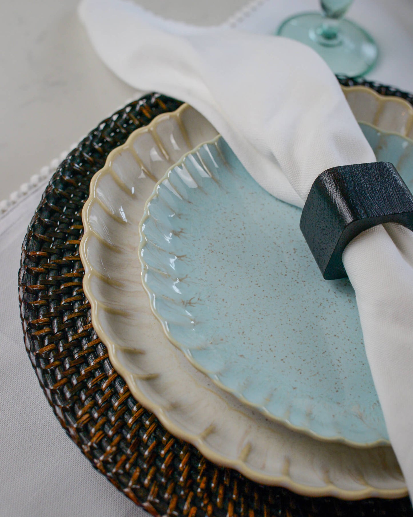 Light blue ceramic plate with a dark woven rattan placemat and white napkin.