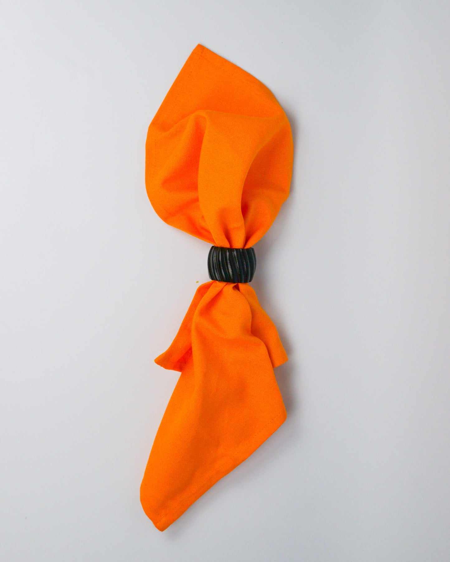 Orange cotton napkin held by a dark wooden napkin ring