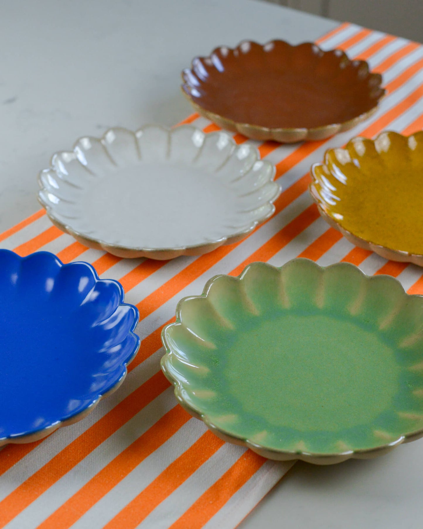 Set of colorful ceramic plates on a striped orange cotton table runner