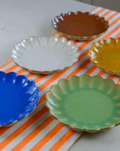 Set of colorful ceramic plates on a striped orange cotton table runner