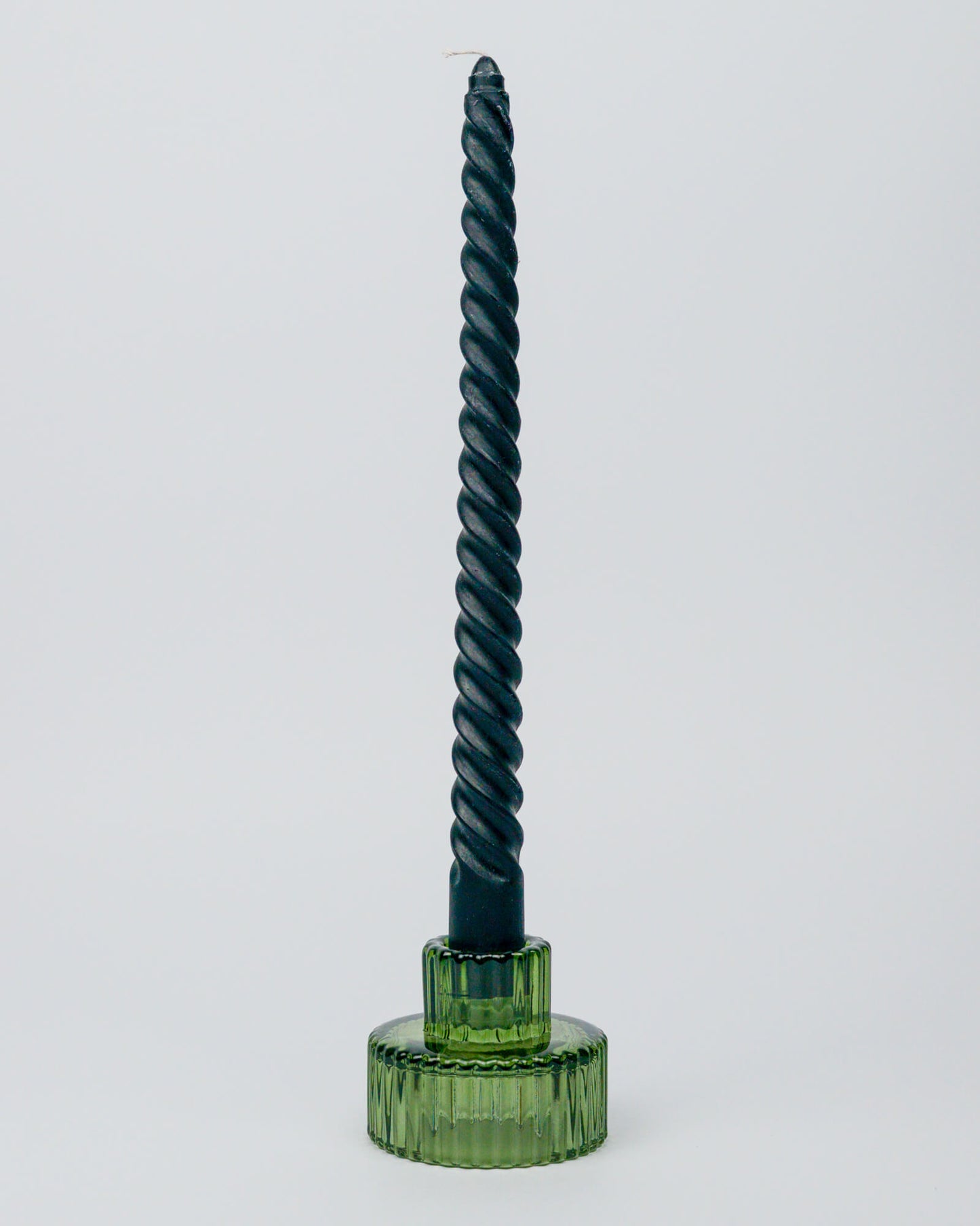 Black twisted candle in a glass green candle holder on a white background