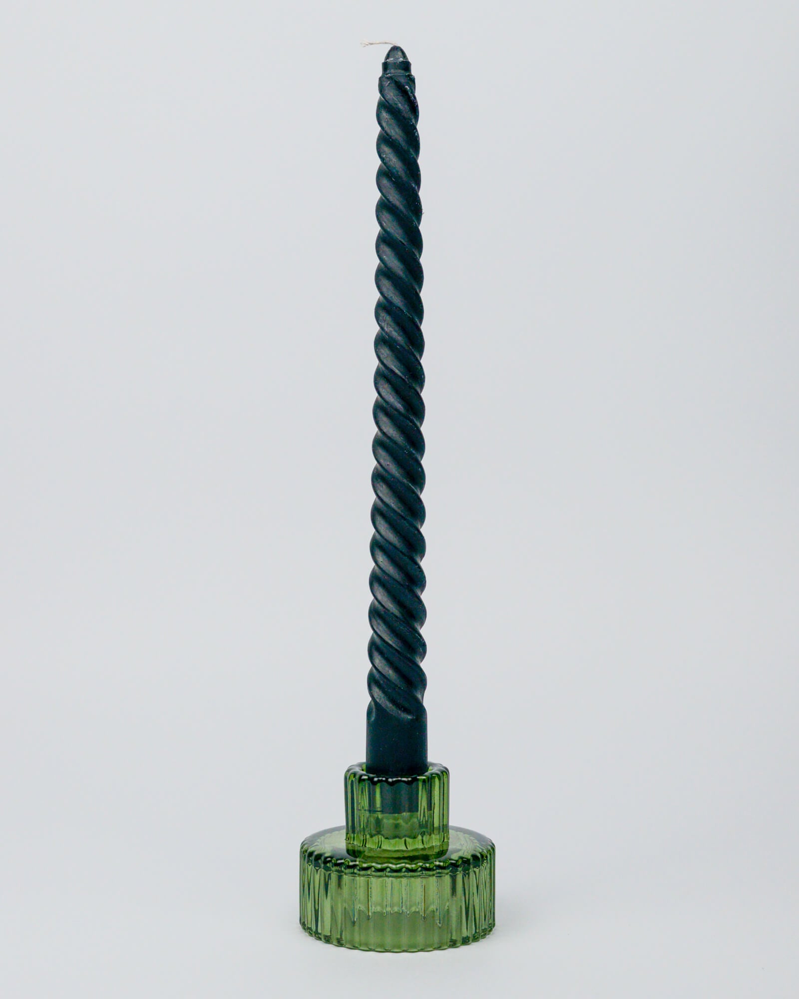 Black twisted candle in a glass green candle holder on a white background