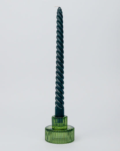 Black twisted candle in a glass green candle holder on a white background