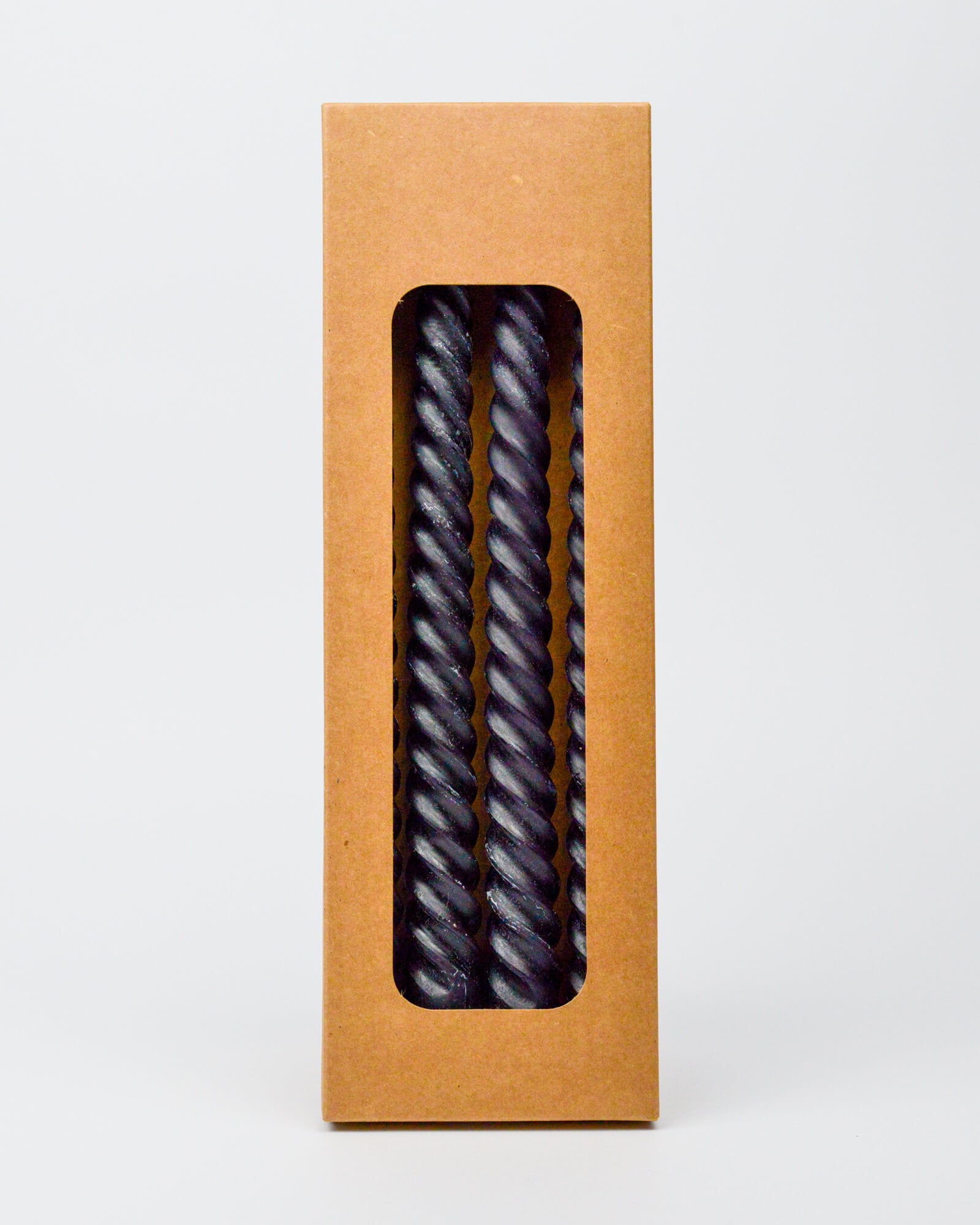 Kraft paper box with a window displaying  twisted black taper candies on a white background