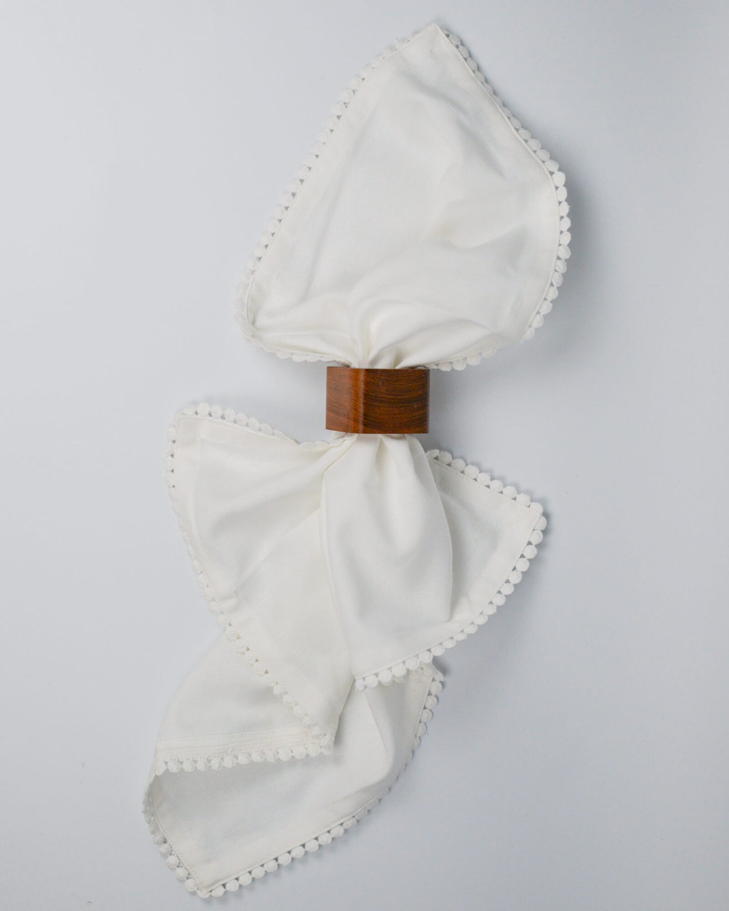 White cotton napkin through a wooden square napkin ring 