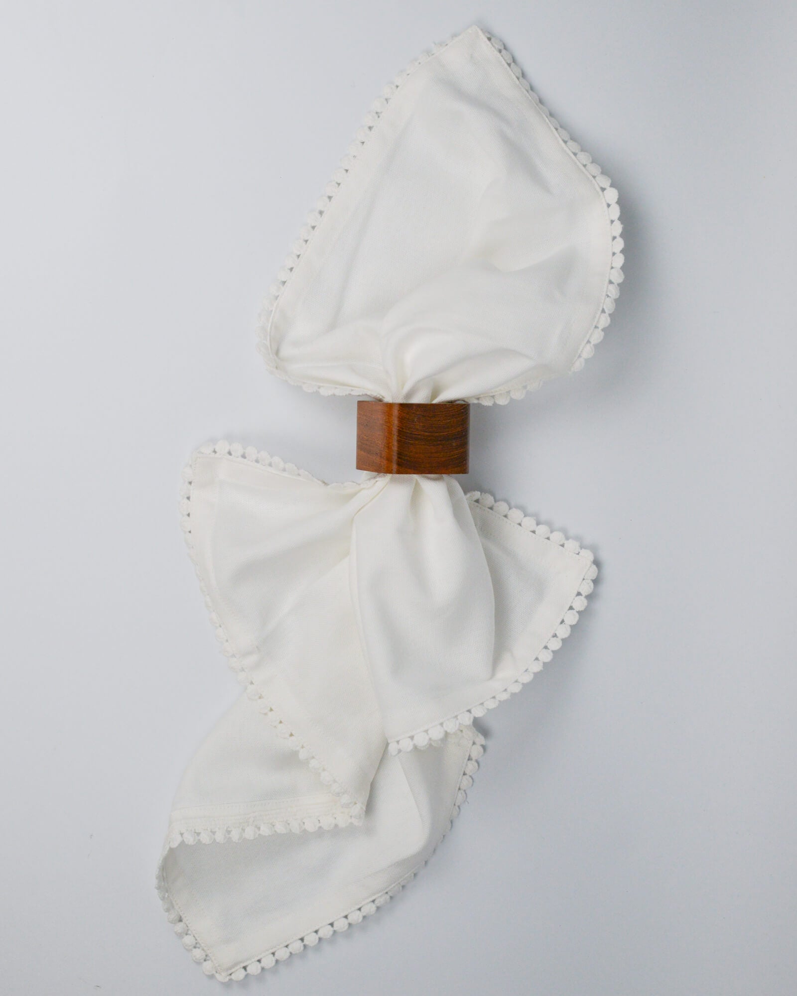 White cotton napkin through a wooden square napkin ring 