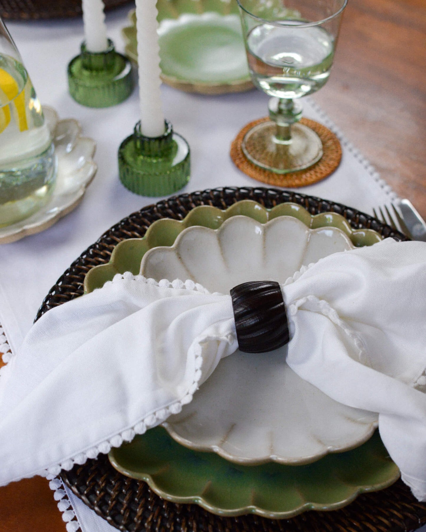 Decorative table setting with a white napkin, dark wooden napkin ring, and green ceramic plate.