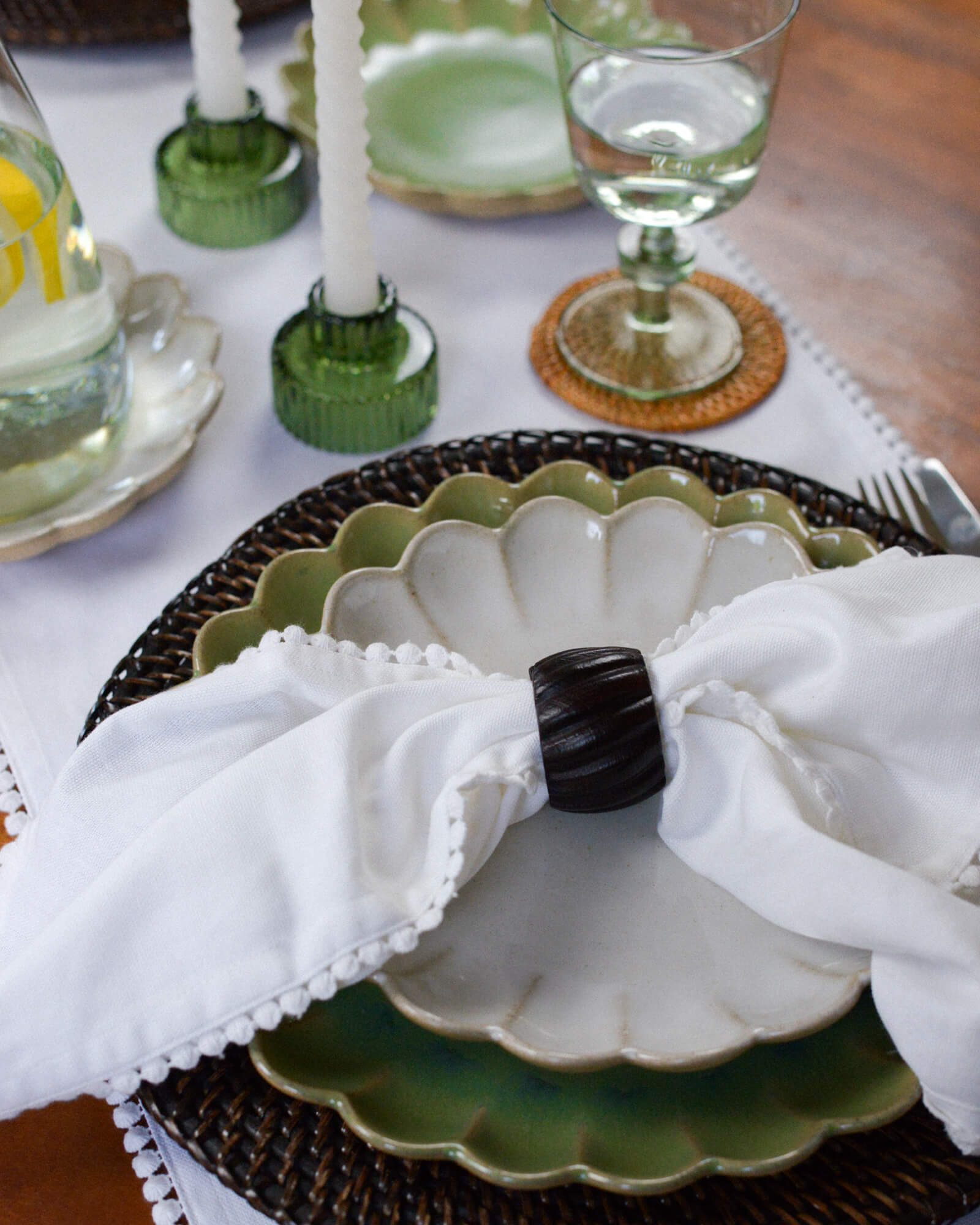 Decorative table setting with a white napkin, dark wooden napkin ring, and green ceramic plate.