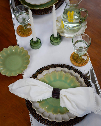 Dining table setting with green plates, white napkins, and glassware.