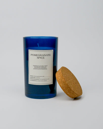 Blue glass jar candle with cork lid labeled 'Pomegranate Spice' with a cork lid on a white background