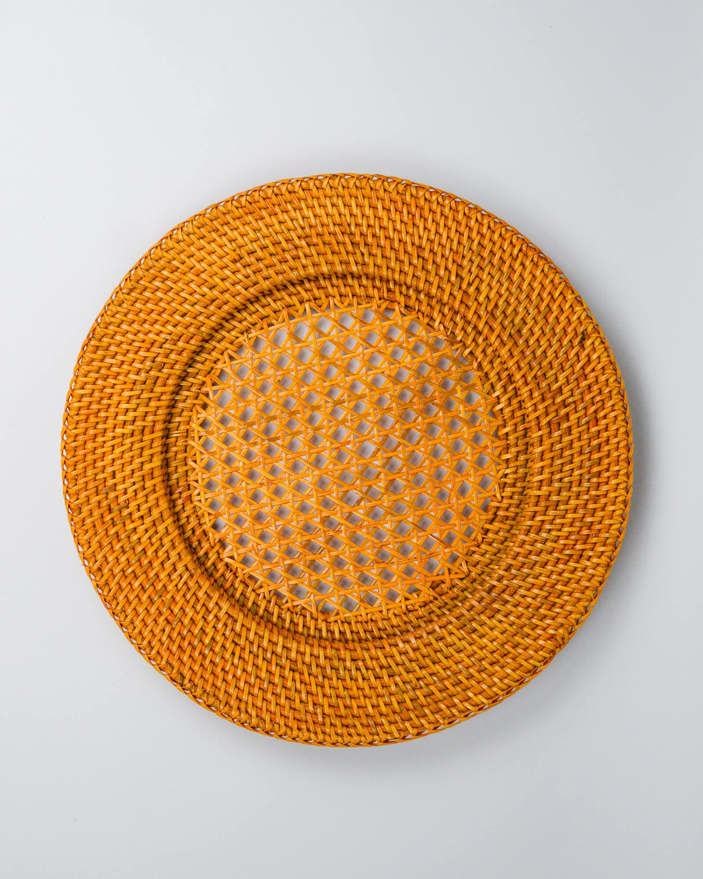 Round woven rattan charger plate on a white background
