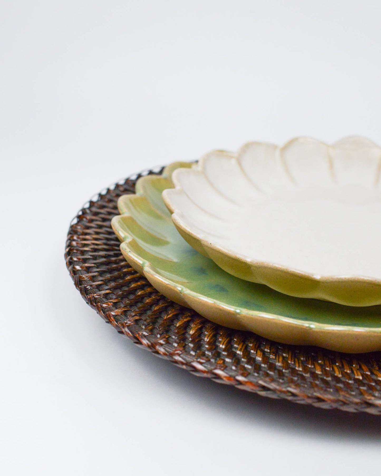 Stack of ceramic plates with rattan charger plate on a white background