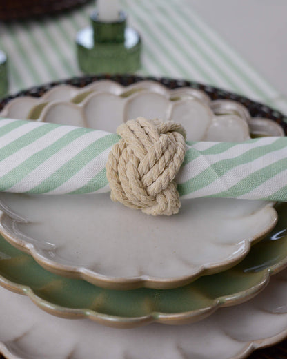 Rope Napkin Ring holding a green striped cotton napkin on a white scalloped side plate