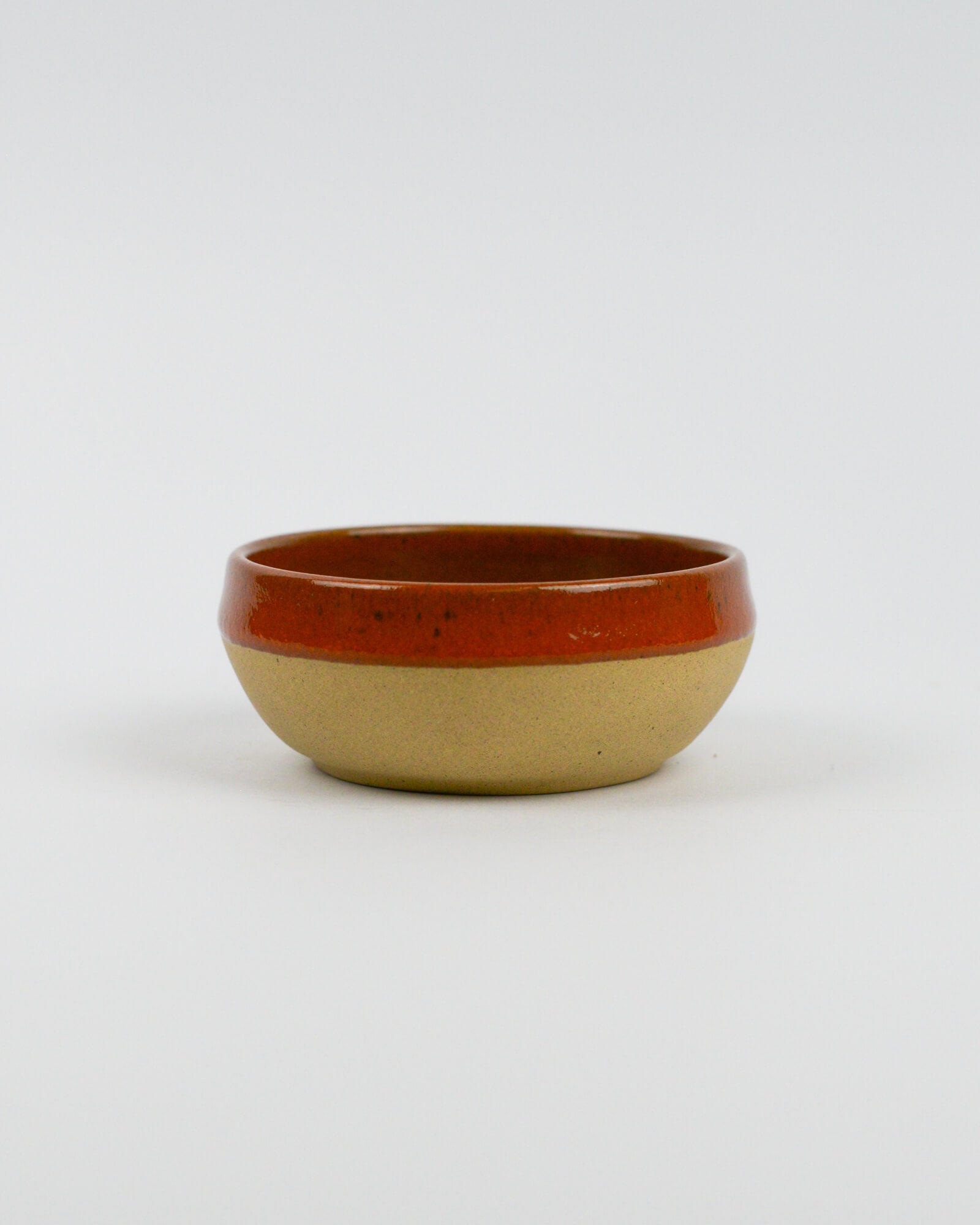Ceramic dipping bowl with a dark red, brown rim on a white background