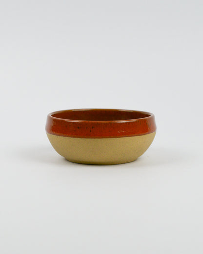 Ceramic dipping bowl with a dark red, brown rim on a white background