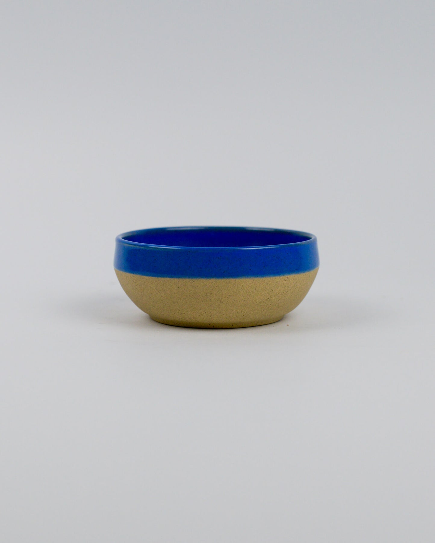 Ceramic stoneware bowl with blue top and beige bottom on a white background