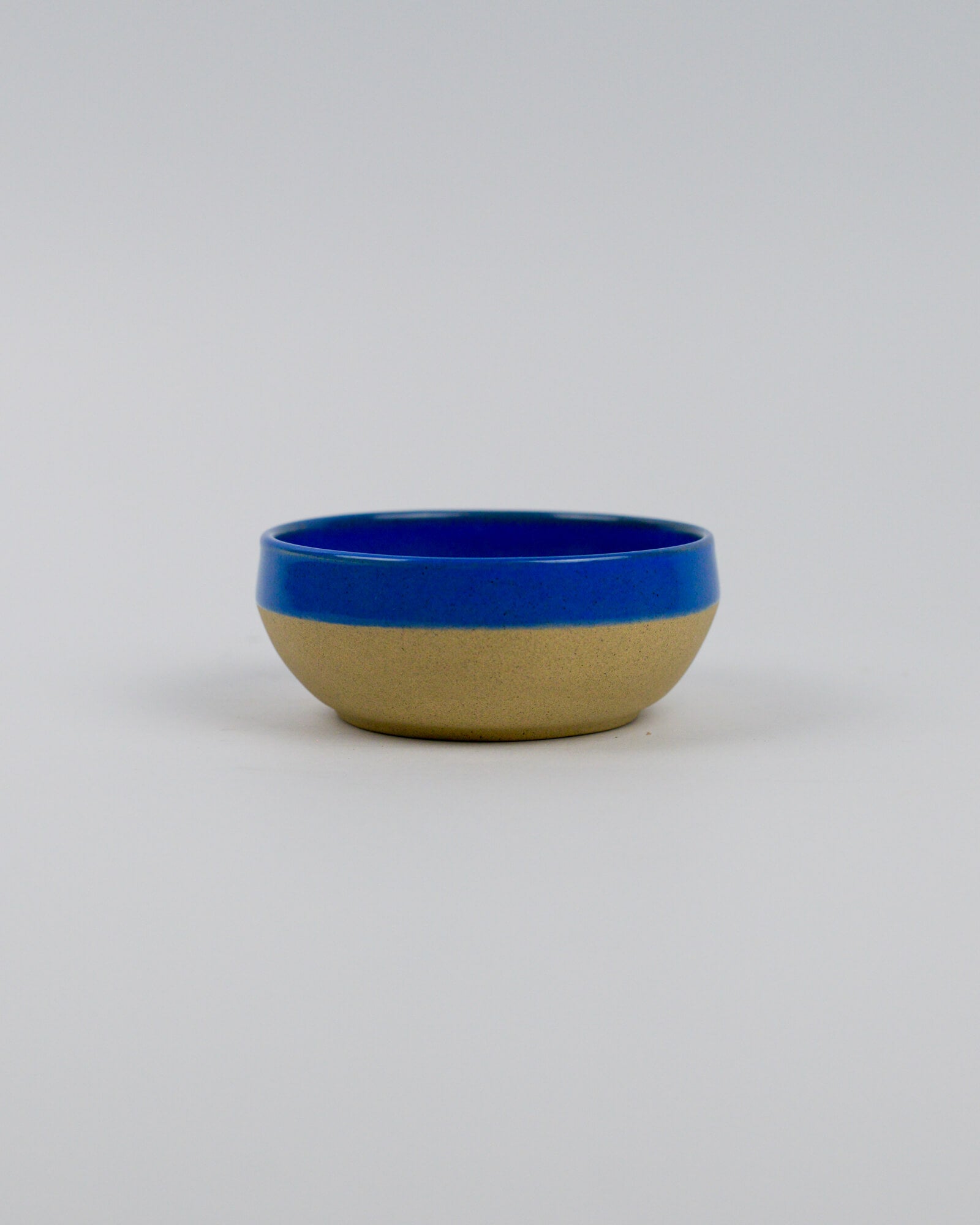 Ceramic stoneware bowl with blue top and beige bottom on a white background