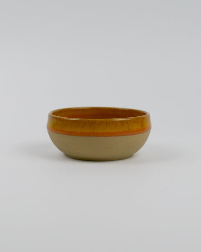 Small ceramic stoneware dipping bowl with a yellow rim on a white background