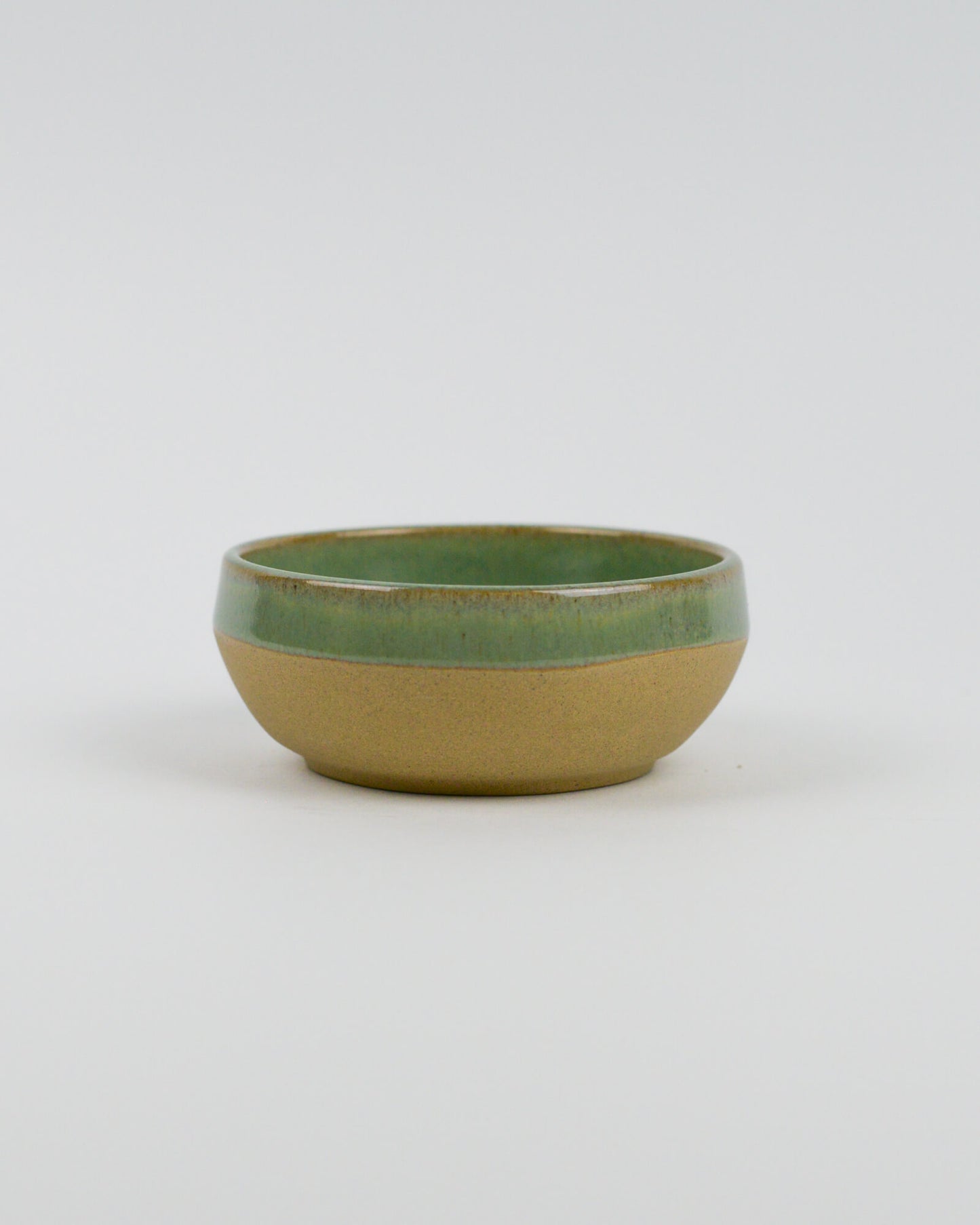 Ceramic bowl with green top and beige bottom on a white background