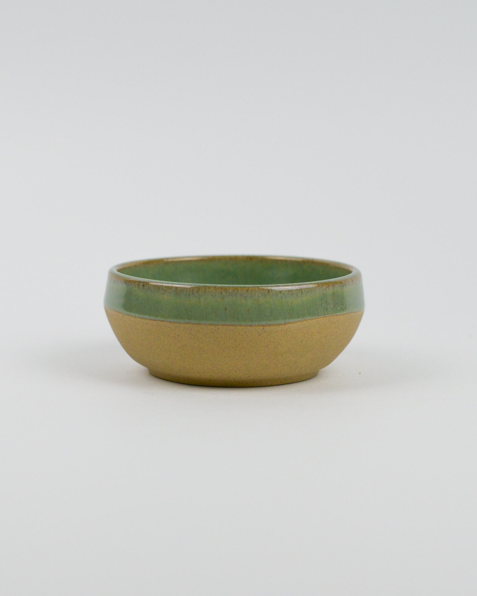 Ceramic bowl with green top and beige bottom on a white background