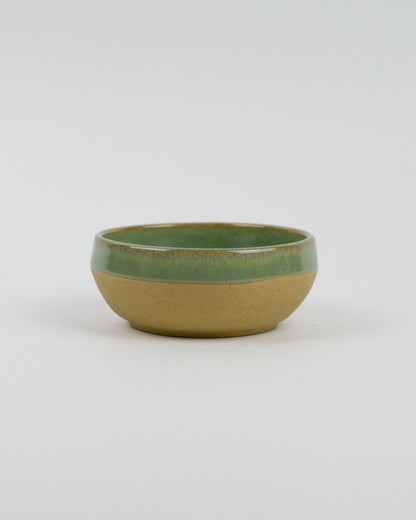 Ceramic bowl with green top and beige bottom on a white background