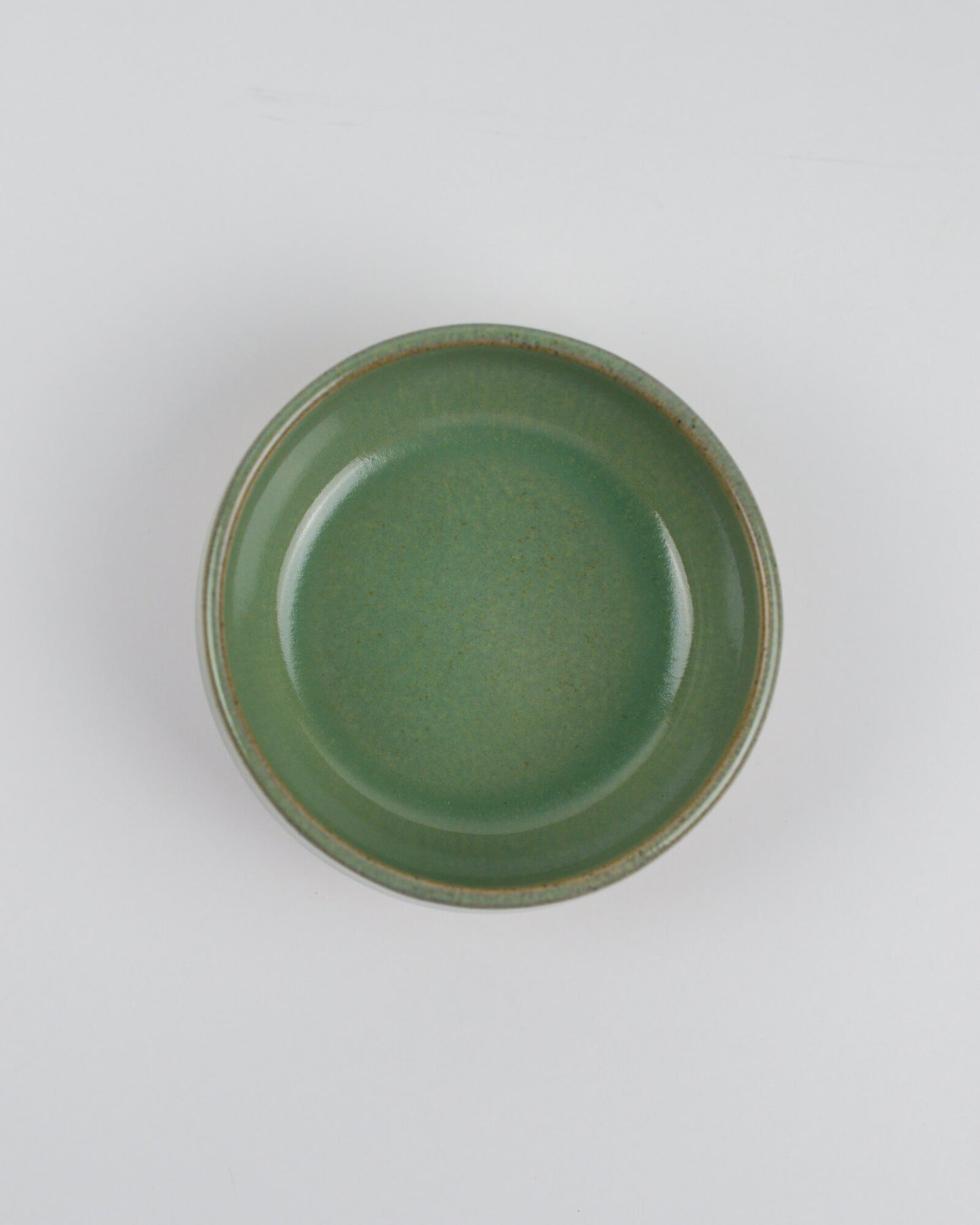 Green ceramic dipping bowl on a white background