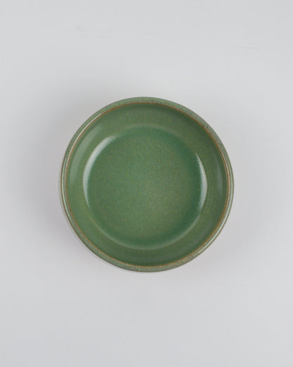 Green ceramic dipping bowl on a white background