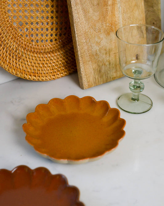 Ceramic scalloped edged yellow appetiser plate on a white marble surface 