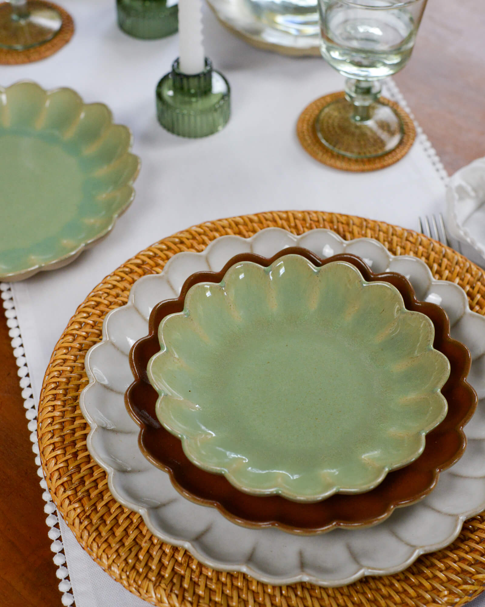 Green ceramic scalloped edge plate on a woven placemat with a white tablecloth.
