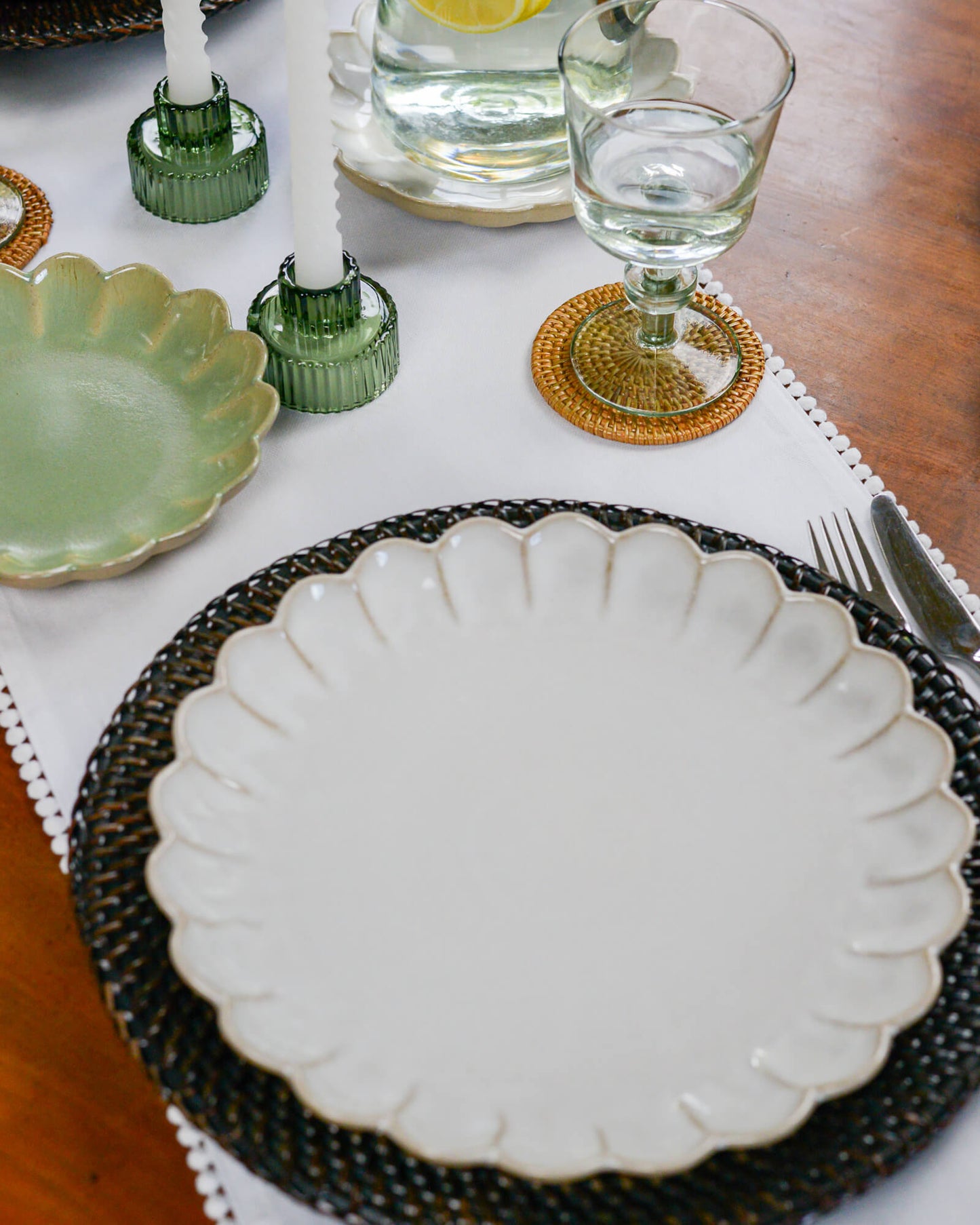 Dining table setting with a white scalloped edge dinner plate, and glassware.