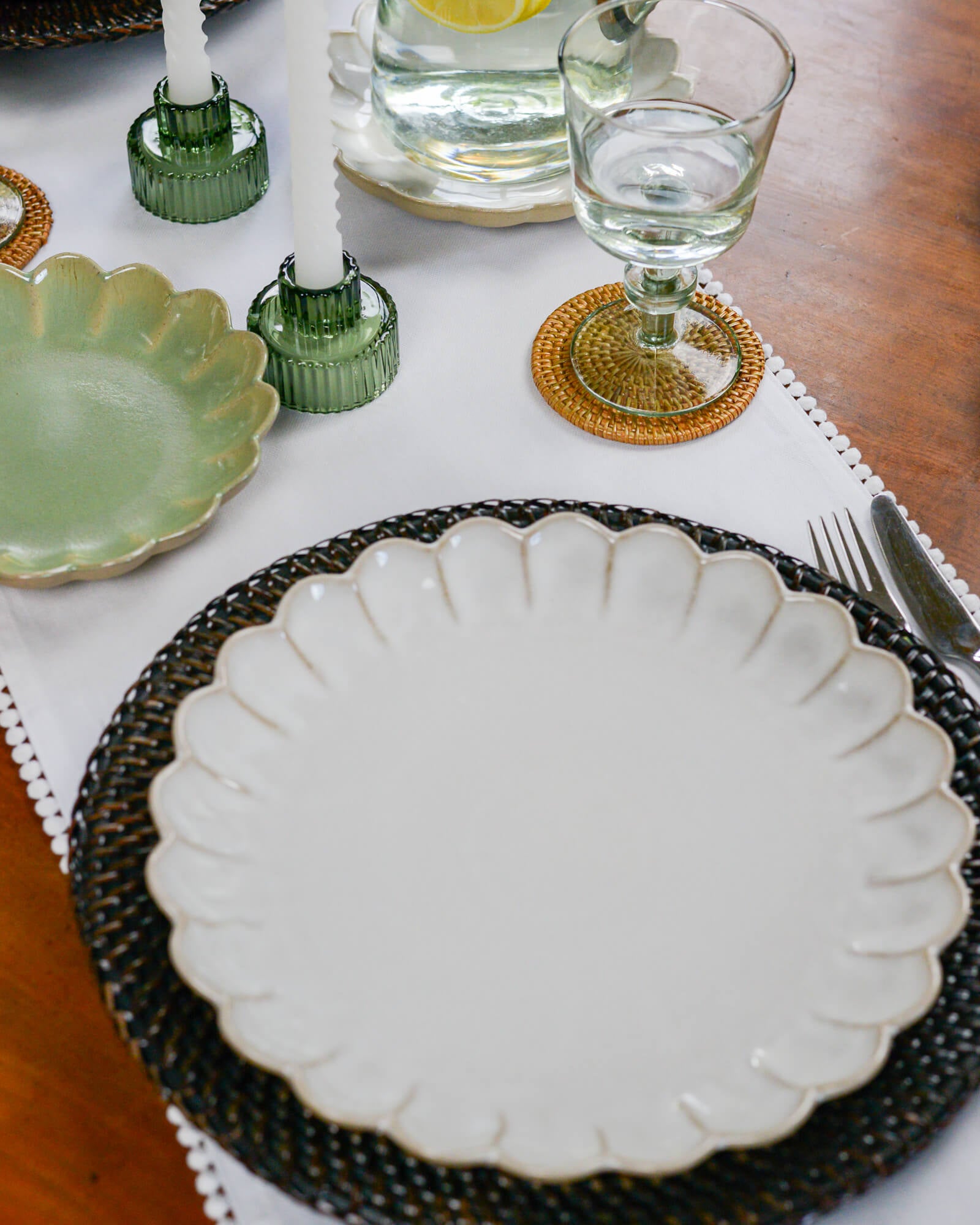 Dining table setting with a white scalloped edge dinner plate, and glassware.