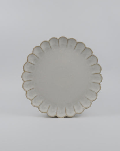 Round ceramic dinner plate with a decorative scalloped edge on a white background