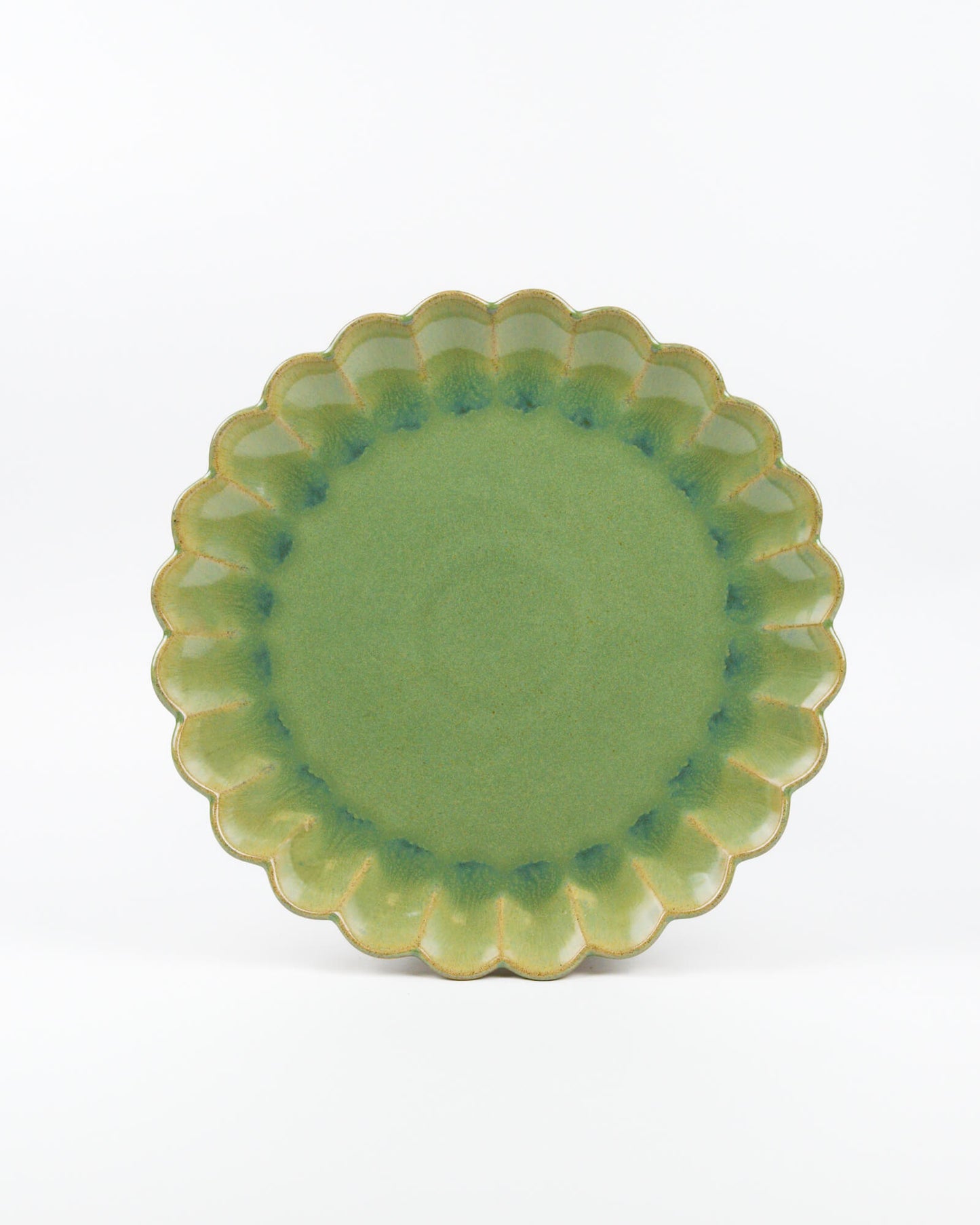 Green ceramic plate with scalloped edge on a white background