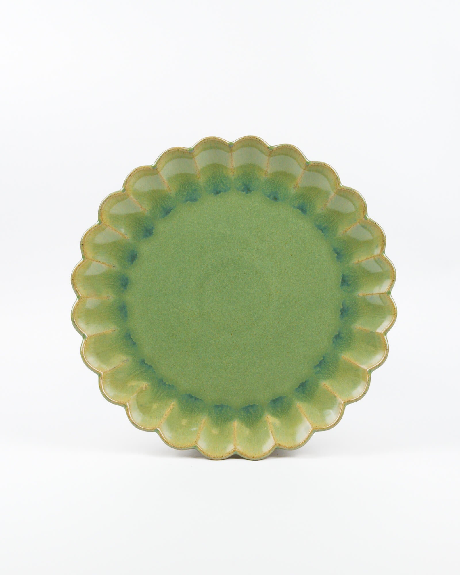 Green ceramic plate with scalloped edge on a white background