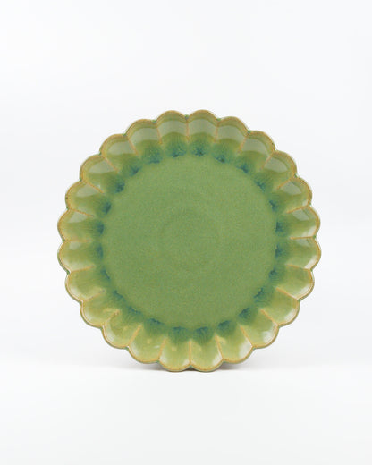Green ceramic plate with scalloped edge on a white background