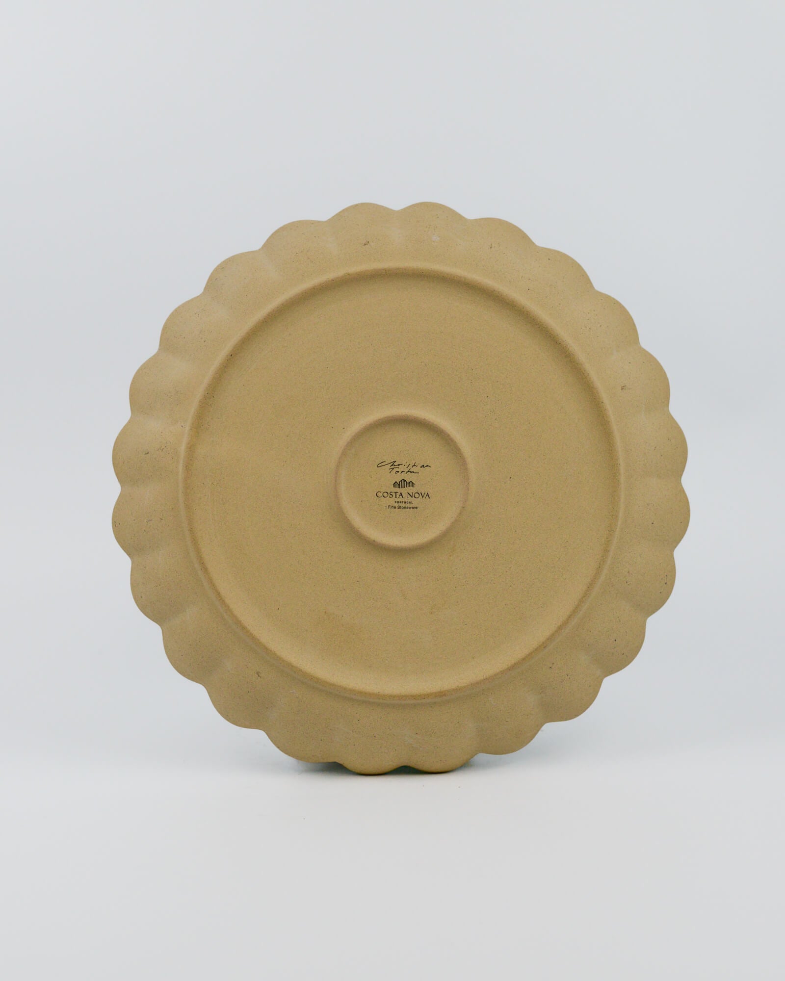 Stoneware ceramic plate with scalloped edge on a white background