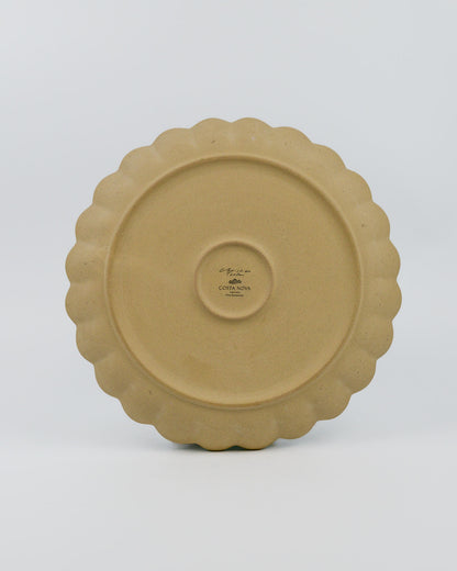 Stoneware ceramic plate with scalloped edge on a white background