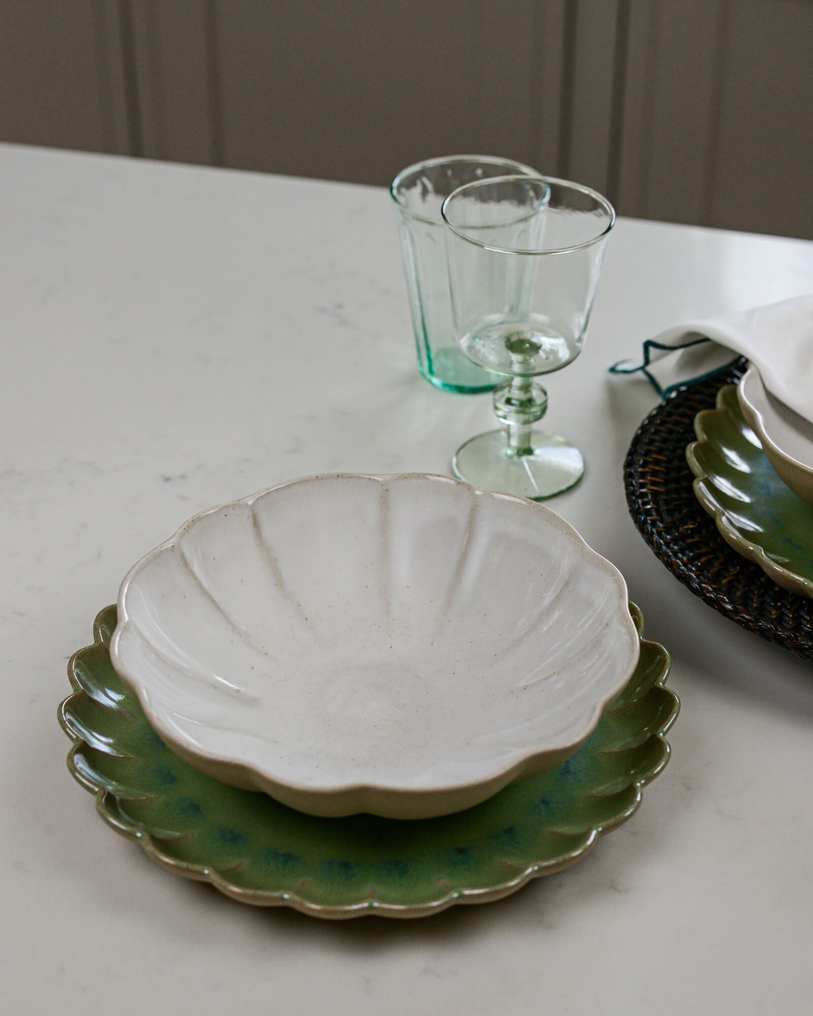 Ceramic pasta bowl with green scalloped edge plate on a white marble surface
