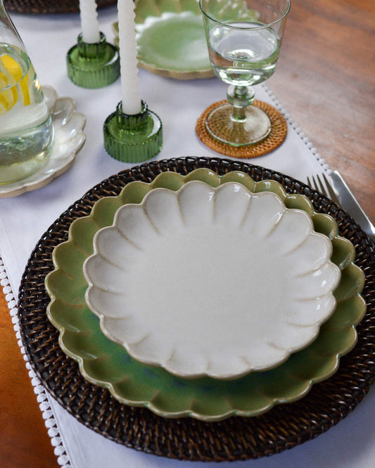 Decorative table setting with a scalloped-edge dessert plate on a woven rattan charger plate.