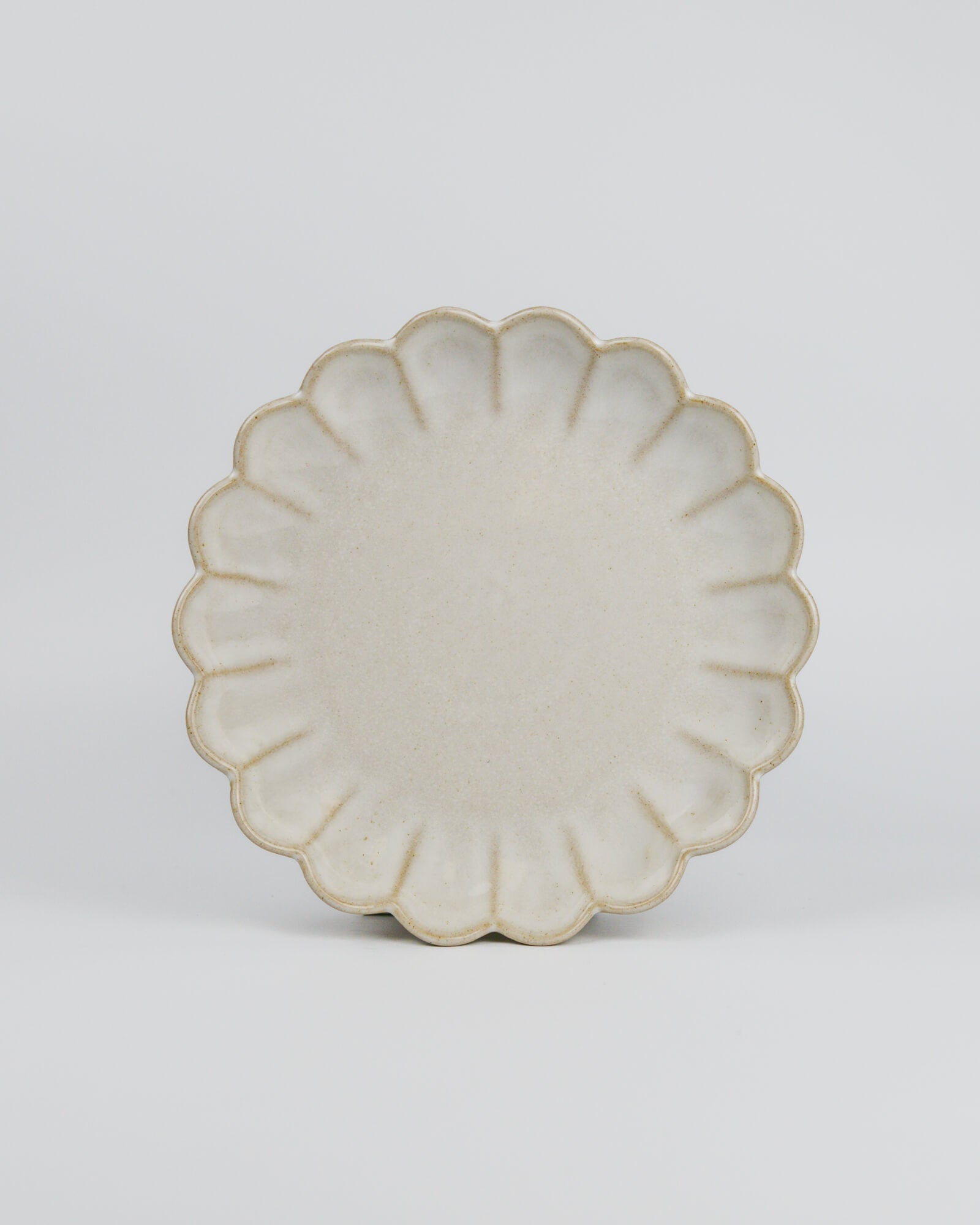 Decorative ceramic dessert plate with a floral scalloped edge on a white background