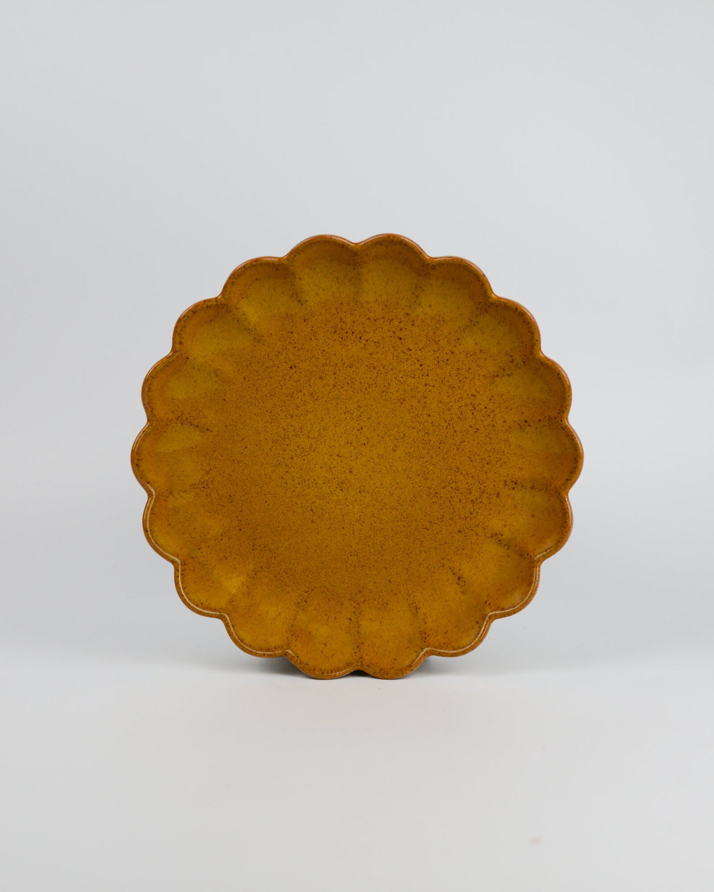 Yellow ceramic plate with scalloped edge on a white background
