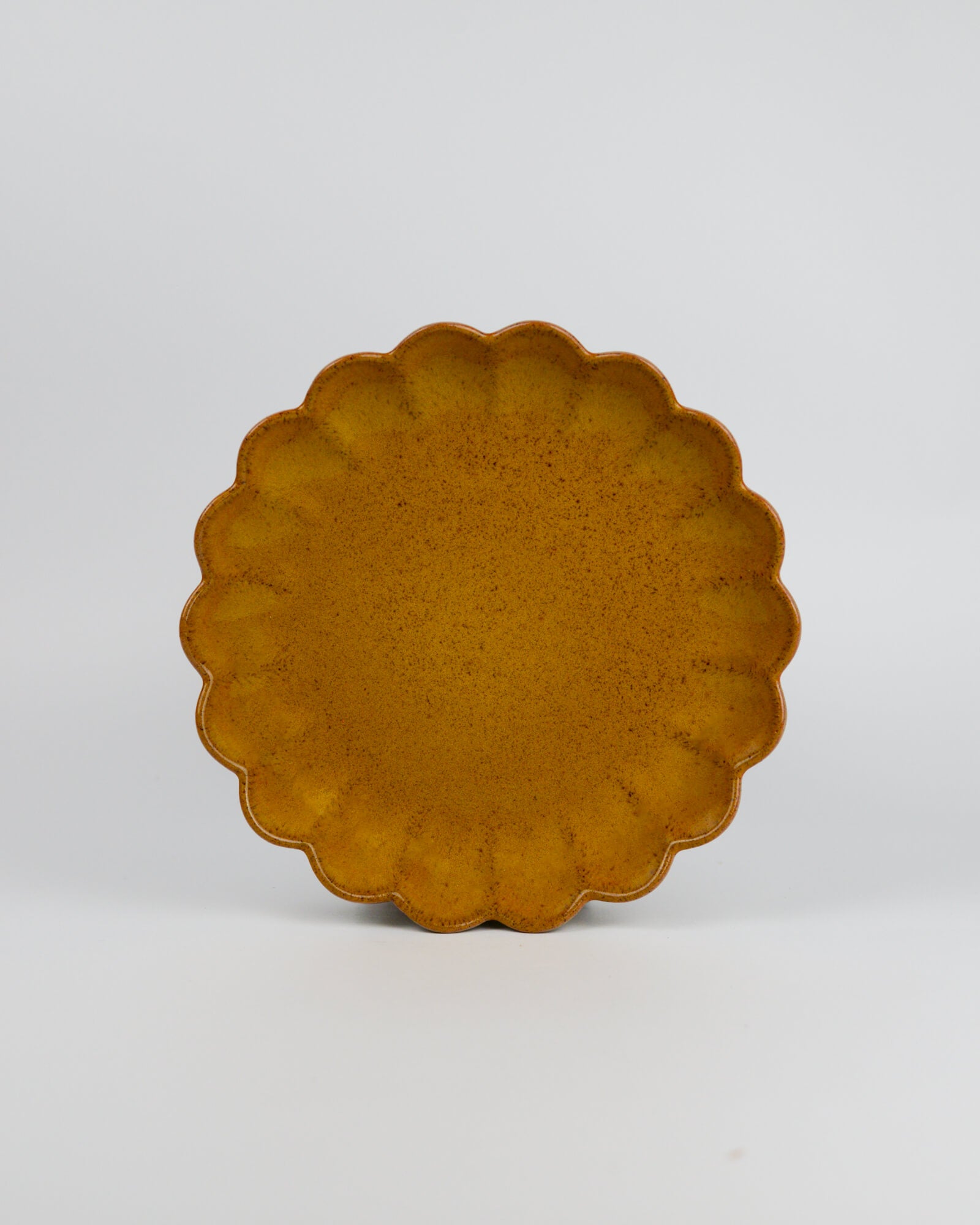 Yellow ceramic plate with scalloped edge on a white background