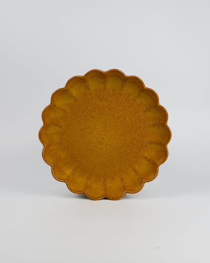 Yellow ceramic plate with scalloped edge on a white background