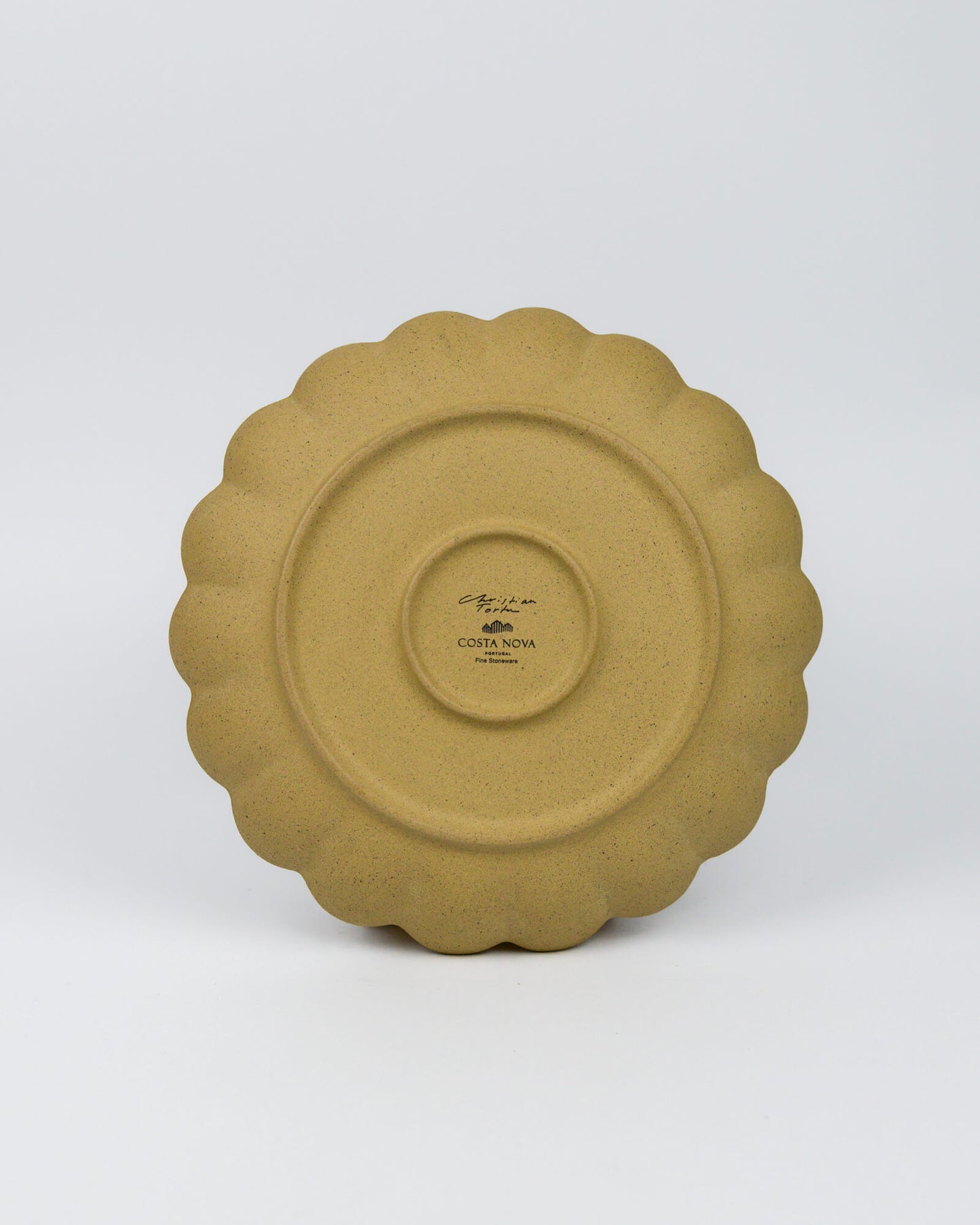 Yellow ceramic plate with scalloped edge on a white background
