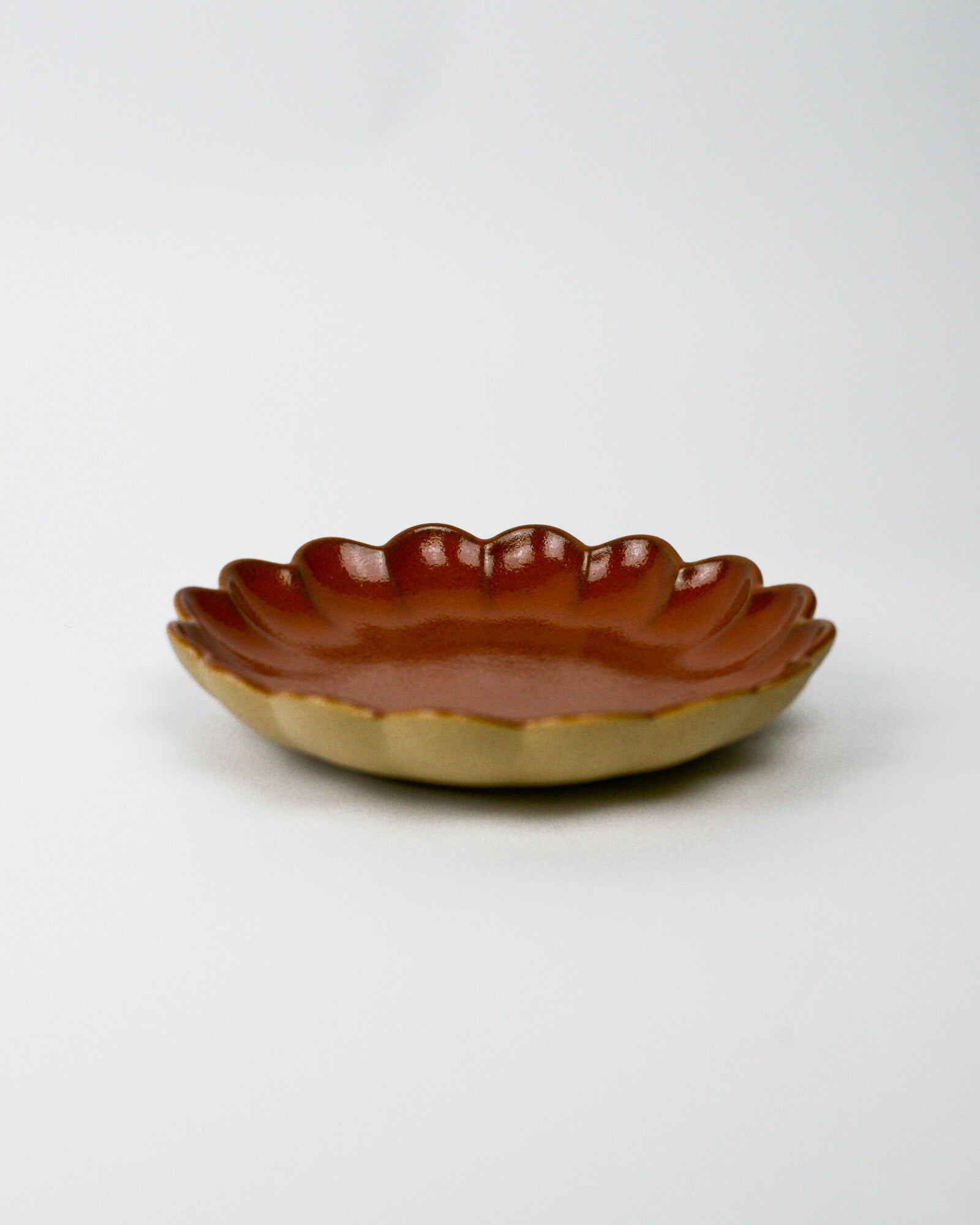 Small ceramic dish with a scalloped edge on a white background